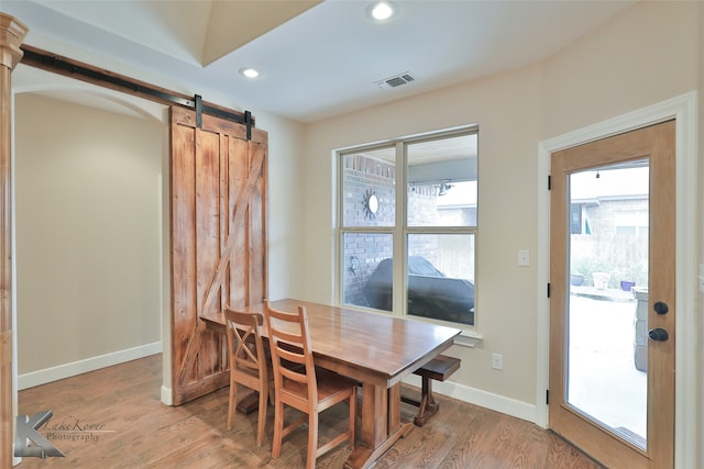 dining room with a barn door, light wood-style flooring, recessed lighting, visible vents, and baseboards