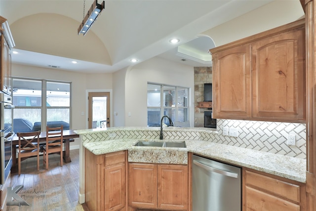 kitchen with a peninsula, light stone counters, stainless steel appliances, and a sink