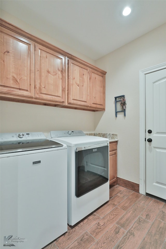 clothes washing area featuring cabinet space, baseboards, light wood finished floors, and washer and dryer