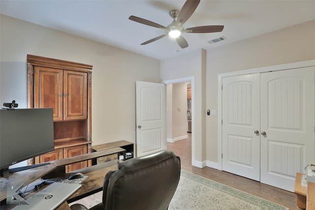 home office featuring visible vents, ceiling fan, baseboards, and wood finished floors