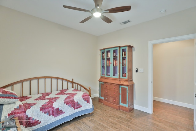 bedroom with ceiling fan, wood finished floors, visible vents, and baseboards