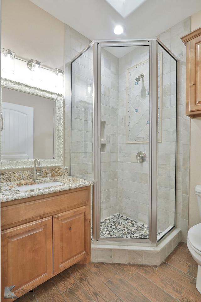 full bath with vanity, a shower stall, toilet, and wood finished floors