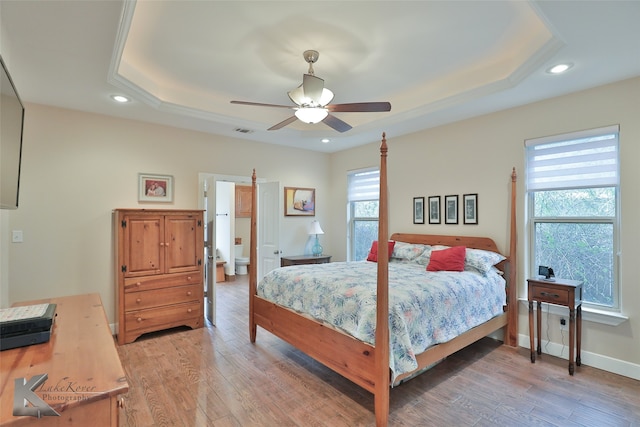 bedroom with light wood-style floors, visible vents, a raised ceiling, and recessed lighting