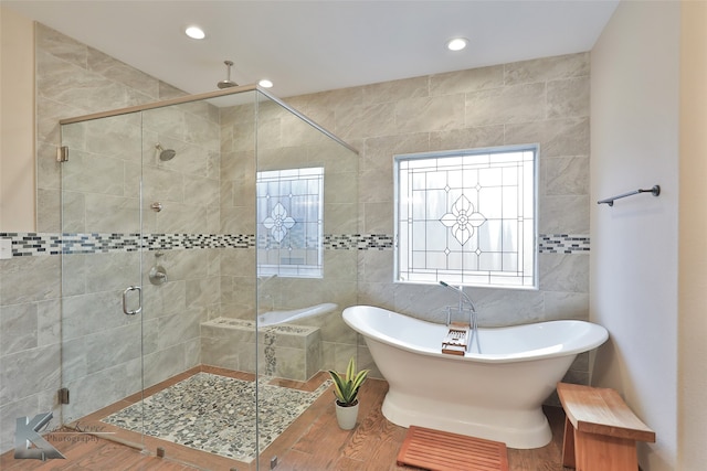 full bath with recessed lighting, a freestanding tub, tile walls, and a shower stall