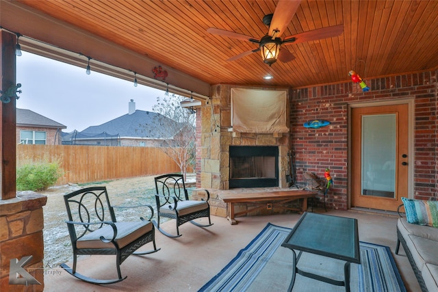 view of patio / terrace featuring an outdoor stone fireplace, fence, and ceiling fan