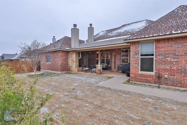 rear view of house featuring a patio area, fence, a chimney, and brick siding