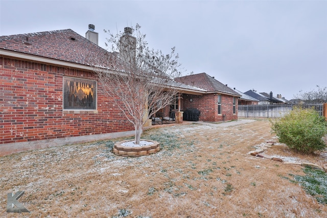 rear view of property with a chimney, fence, and brick siding