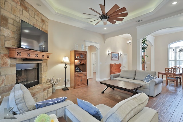 living room with arched walkways, a tray ceiling, visible vents, and crown molding