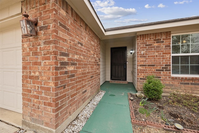 property entrance featuring a garage and brick siding