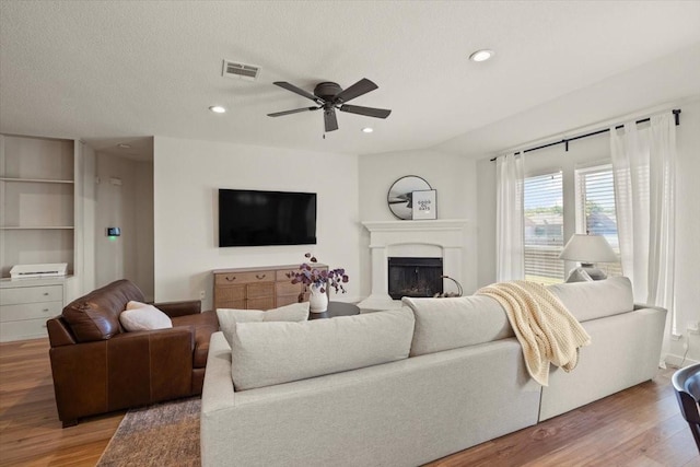 living room with recessed lighting, a fireplace, visible vents, and light wood-style floors