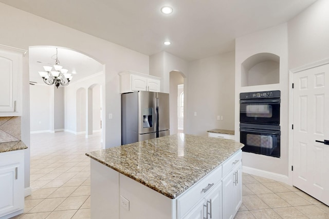 kitchen with light stone counters, stainless steel refrigerator with ice dispenser, light tile patterned floors, dobule oven black, and white cabinets