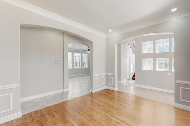 spare room featuring ornamental molding, arched walkways, stairs, and light tile patterned floors