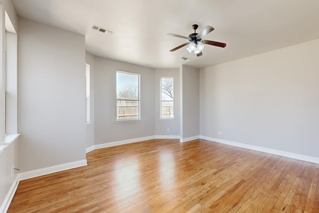 empty room with light wood-style floors, visible vents, baseboards, and a ceiling fan