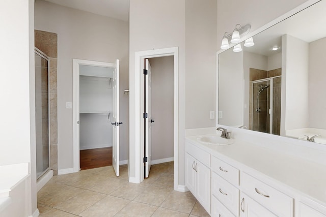 bathroom with tile patterned flooring, vanity, baseboards, a stall shower, and a walk in closet