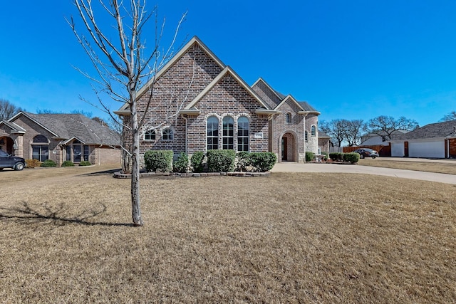 french provincial home with a front yard and brick siding