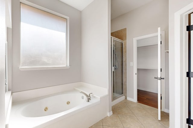 bathroom with a stall shower, baseboards, a tub with jets, and tile patterned floors