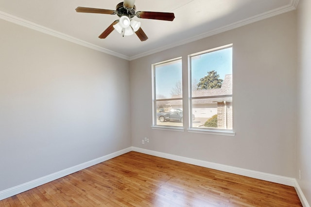 spare room with ornamental molding, light wood finished floors, and baseboards