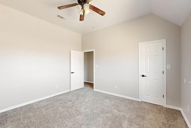 carpeted spare room with lofted ceiling, ceiling fan, visible vents, and baseboards