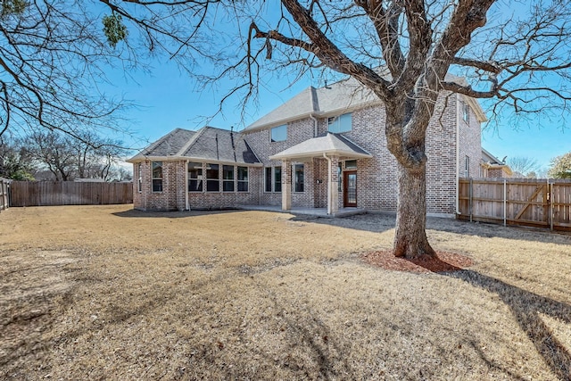 rear view of house with a yard, a fenced backyard, and brick siding