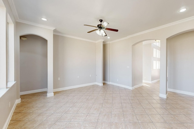 empty room with arched walkways, ornamental molding, a ceiling fan, and baseboards