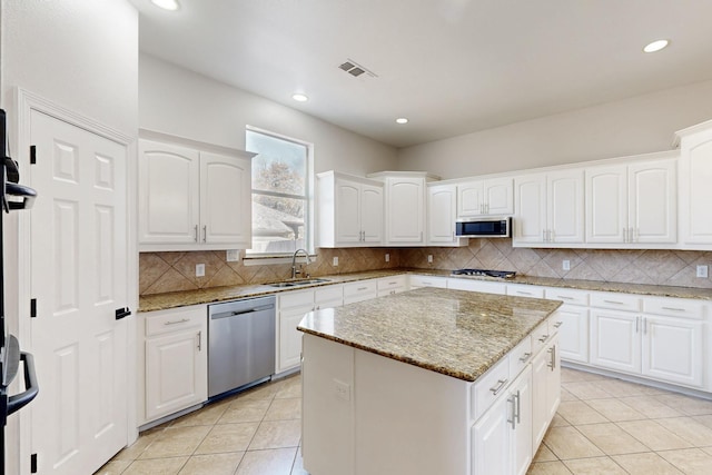 kitchen featuring a center island, stainless steel appliances, decorative backsplash, light tile patterned flooring, and a sink