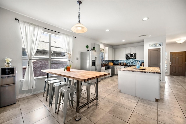 kitchen with stainless steel appliances, tasteful backsplash, light tile patterned flooring, and a sink