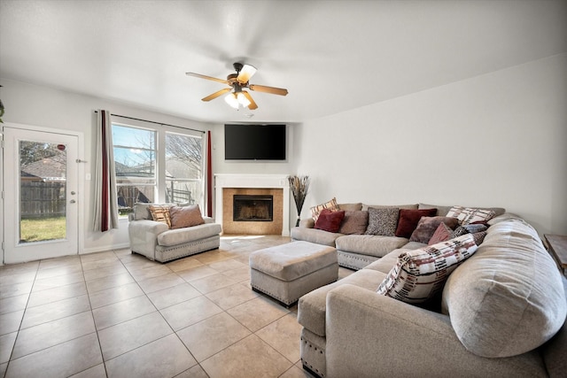 living room featuring a ceiling fan, a fireplace, and light tile patterned floors