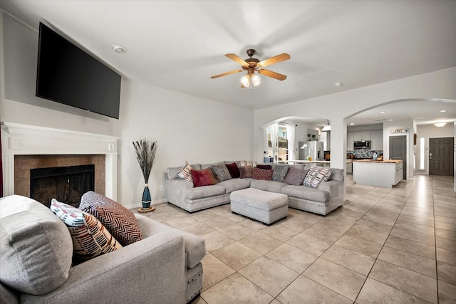 living room featuring arched walkways, light tile patterned floors, recessed lighting, a fireplace, and a ceiling fan