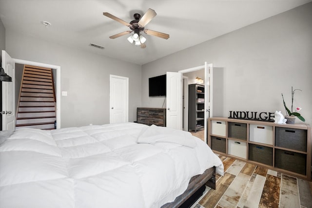 bedroom with ceiling fan, visible vents, and wood finished floors