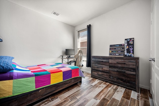 bedroom featuring wood finished floors, visible vents, and baseboards