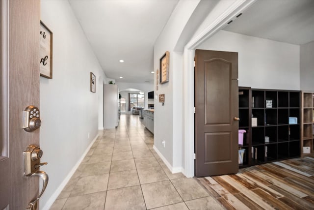 hall with arched walkways, light tile patterned flooring, baseboards, and recessed lighting