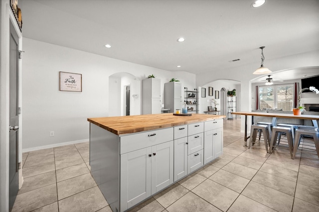 kitchen with arched walkways, wooden counters, and light tile patterned floors