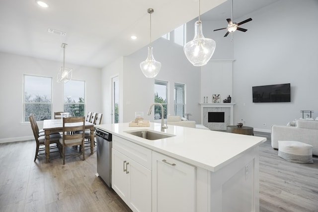 kitchen featuring visible vents, dishwasher, a premium fireplace, open floor plan, and a sink