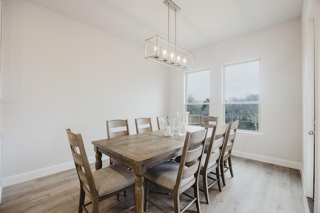 dining room with light wood-type flooring, baseboards, and an inviting chandelier