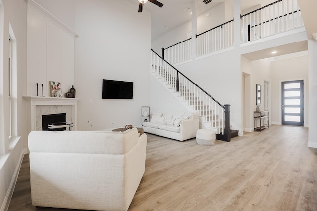 living area featuring stairs, baseboards, wood finished floors, and a high end fireplace