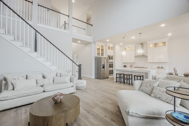 living area with visible vents, baseboards, light wood-style flooring, stairway, and recessed lighting