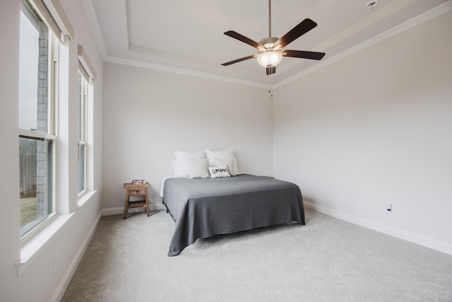 carpeted bedroom with baseboards, a raised ceiling, a ceiling fan, and crown molding