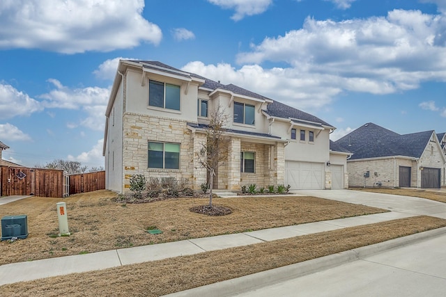 view of front of property featuring stucco siding, fence, a garage, stone siding, and driveway