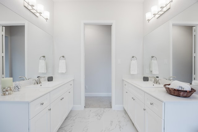 bathroom with marble finish floor, two vanities, a sink, and baseboards