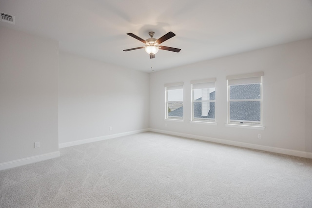 unfurnished room featuring light carpet, visible vents, baseboards, and a ceiling fan