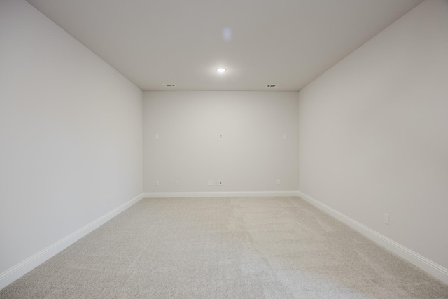 empty room with recessed lighting, light colored carpet, and baseboards