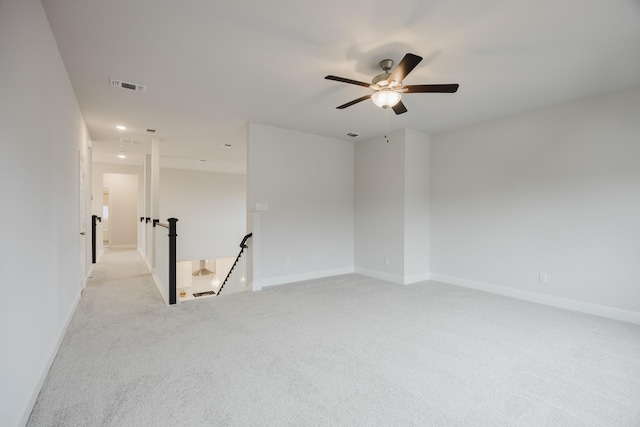 spare room featuring light carpet, a ceiling fan, visible vents, and baseboards