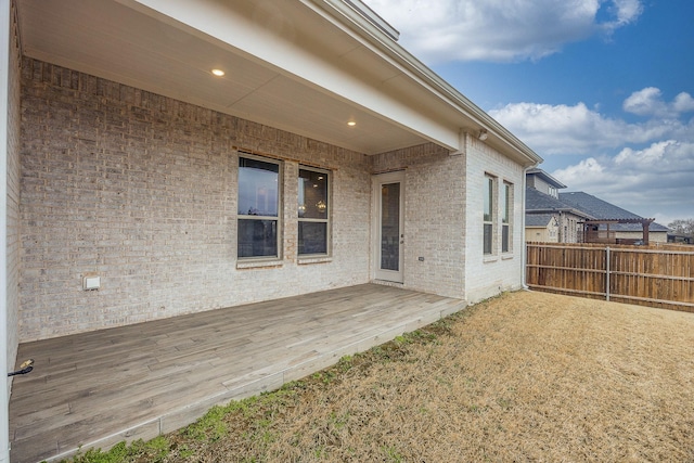 exterior space with brick siding, fence, and a deck