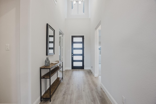 entrance foyer with light wood-type flooring, a high ceiling, baseboards, and a wealth of natural light