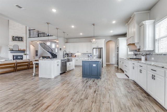 kitchen featuring arched walkways, visible vents, appliances with stainless steel finishes, open floor plan, and a kitchen island