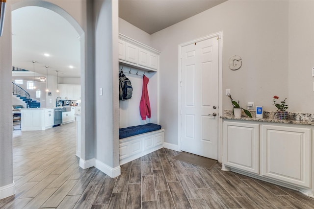 mudroom featuring baseboards, arched walkways, and wood finish floors