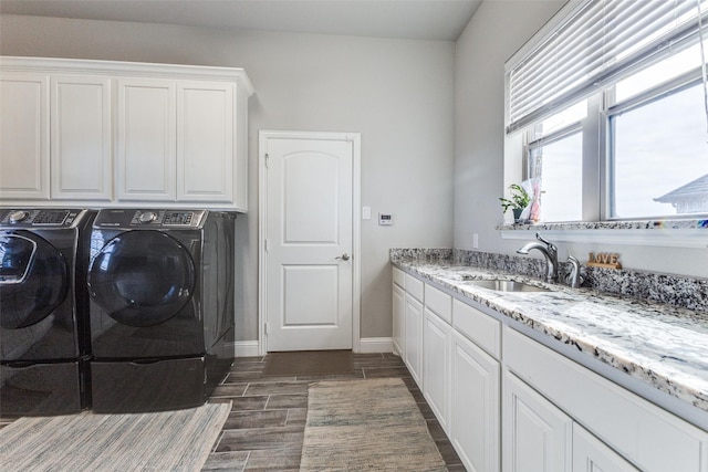 clothes washing area featuring cabinet space, baseboards, washer and clothes dryer, dark wood-style floors, and a sink