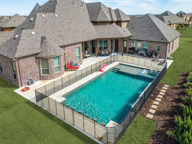 view of pool featuring a pool with connected hot tub, a patio area, a yard, and a fenced backyard