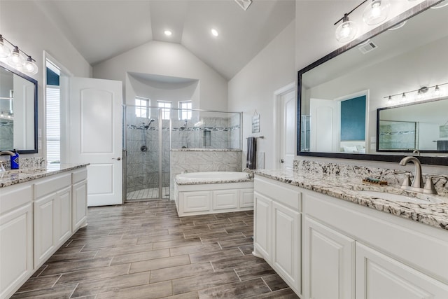 full bathroom with lofted ceiling, a garden tub, wood finish floors, a sink, and a shower stall