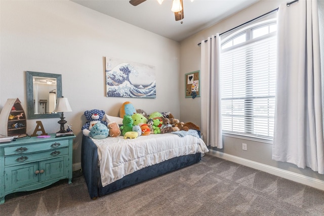 bedroom with baseboards, multiple windows, dark carpet, and ceiling fan